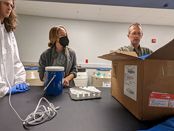 Three people standing around a lab table.